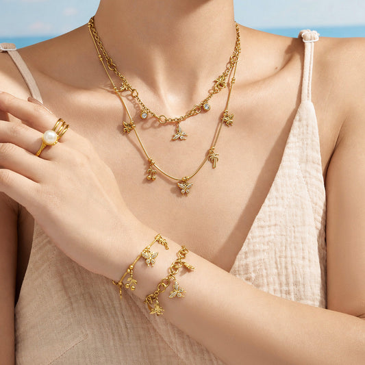 Model styling a gold butterfly charm necklace with the coordinating bracelet