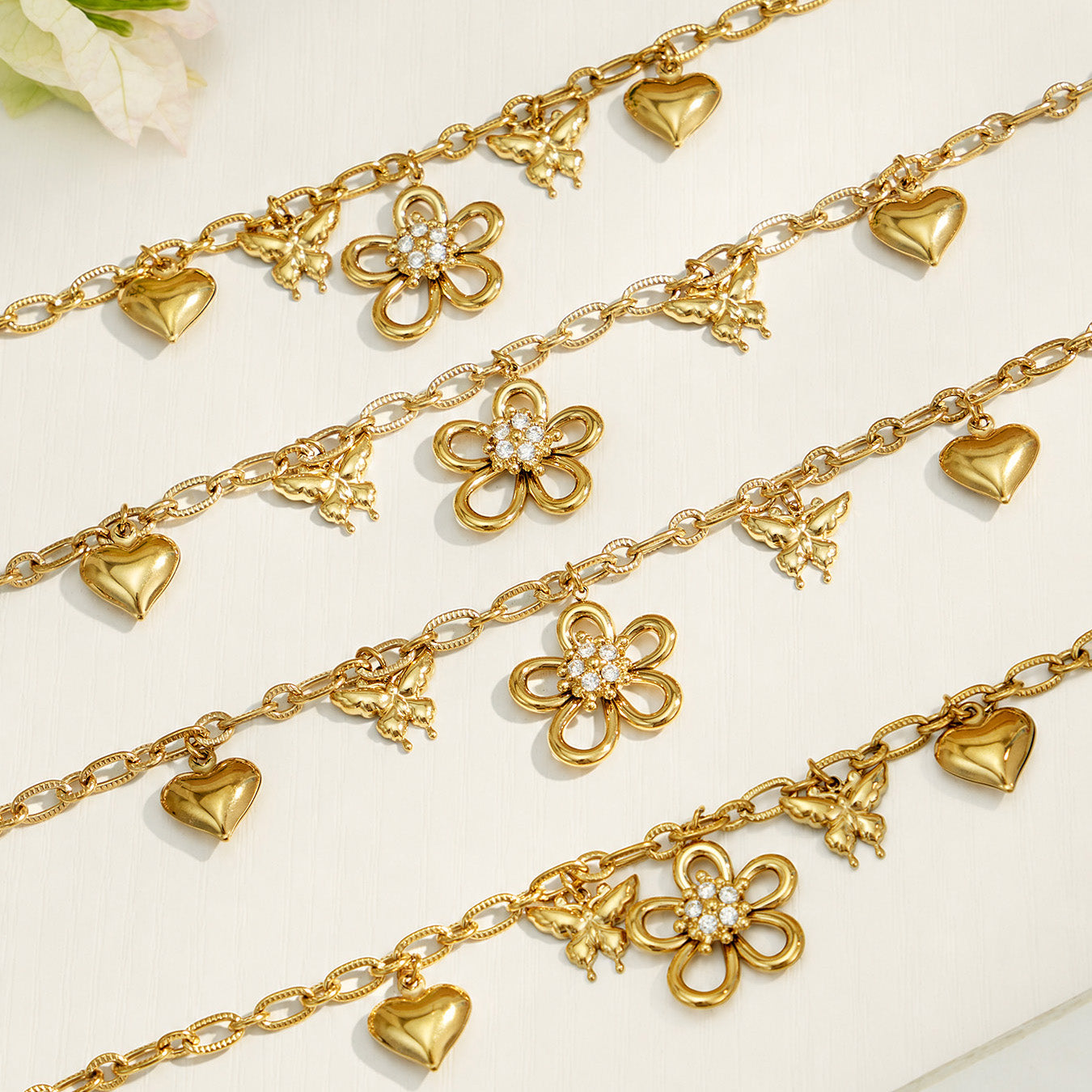 Close-up arrangement of gold butterfly flower and heart charm chains with zircon details