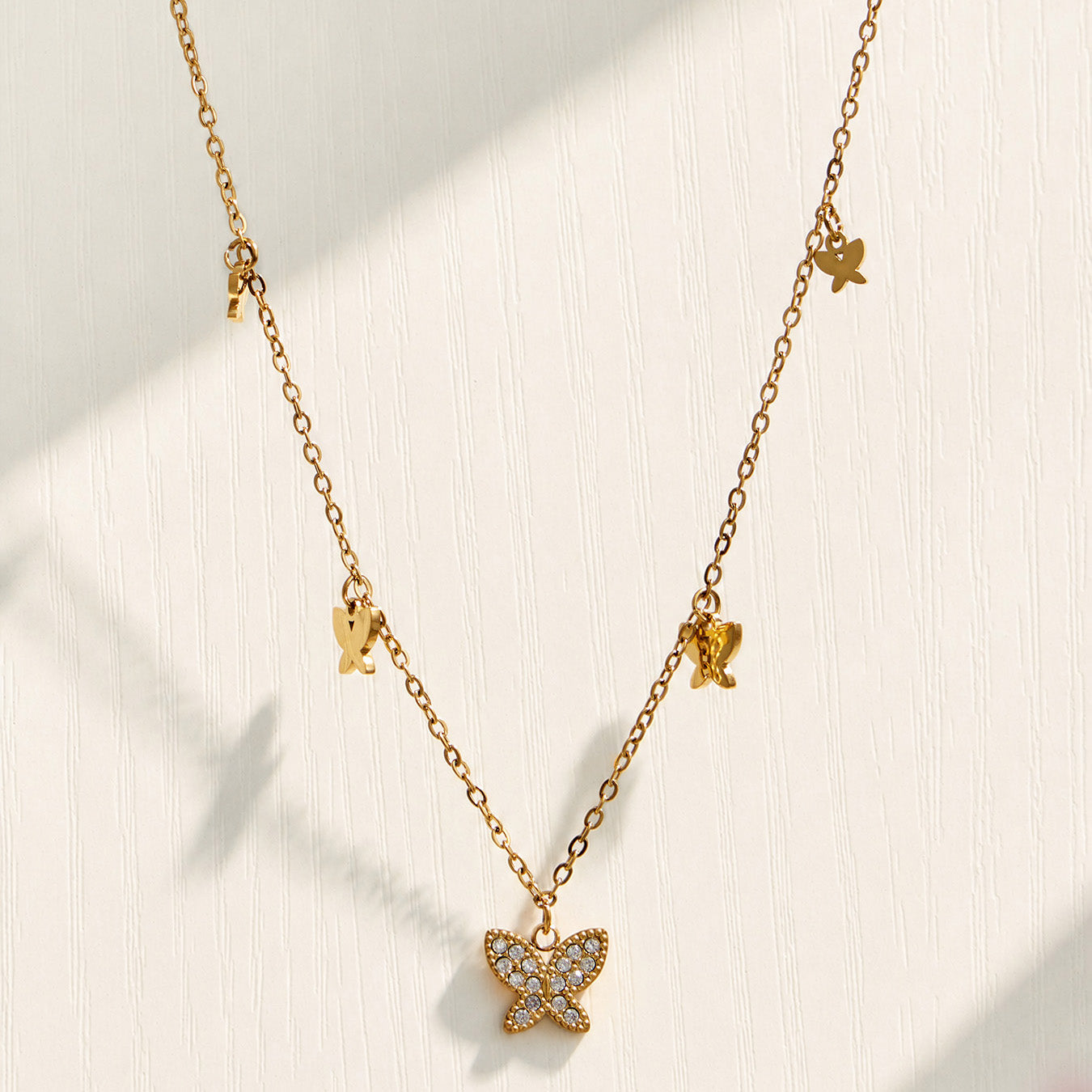 Gold butterfly zircon pendant necklace displayed on a neutral fabric background
