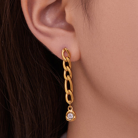 Model wearing a gold link chain drop earring with a clear round zircon accent