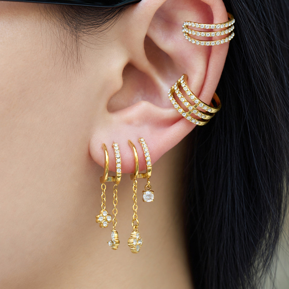 Gold-tone stainless steel CZ dangle earrings styled in a layered ear look