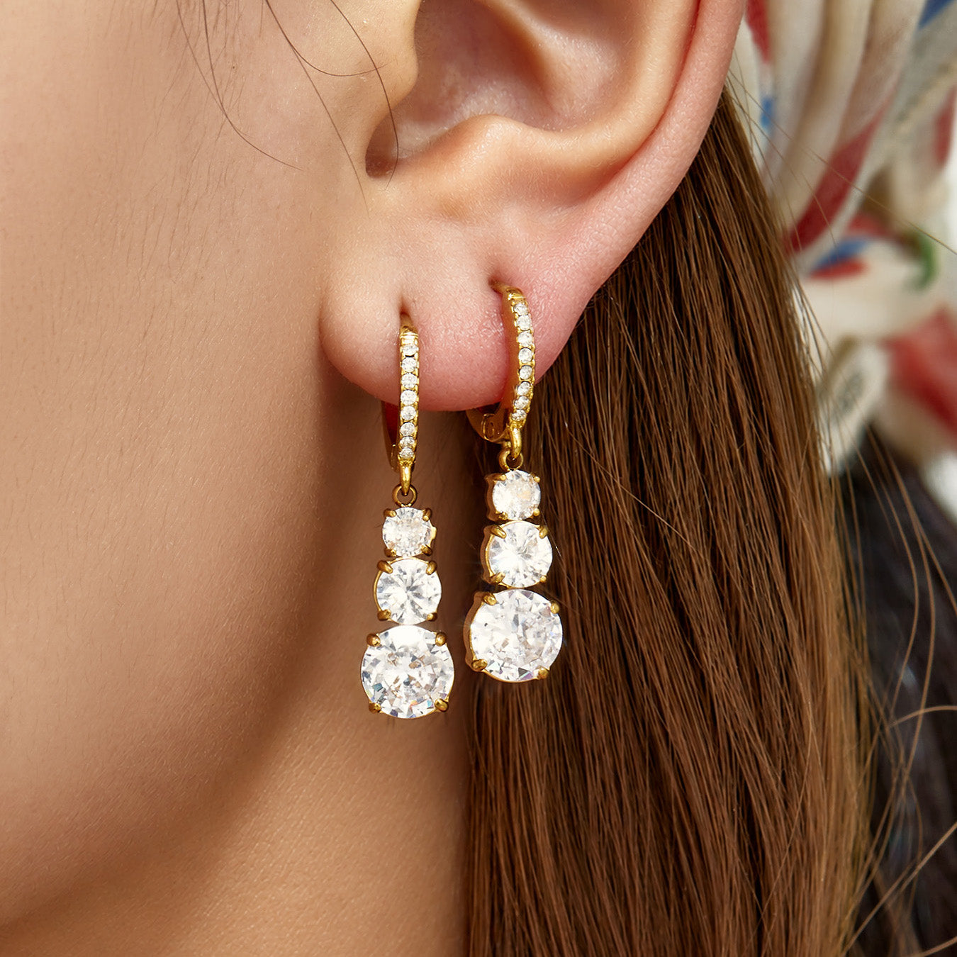 Front view of gold cubic zirconia droplet earrings worn on the ear