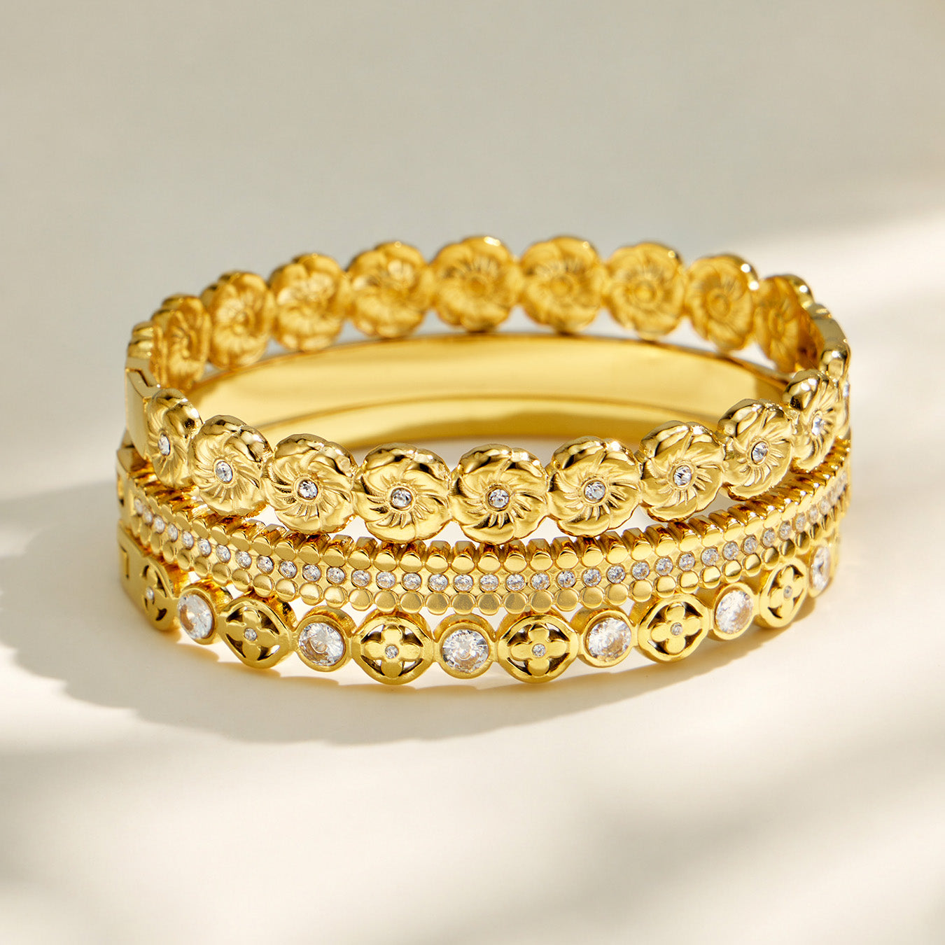 Layered display of gold floral, striped and openwork cubic zirconia bangles