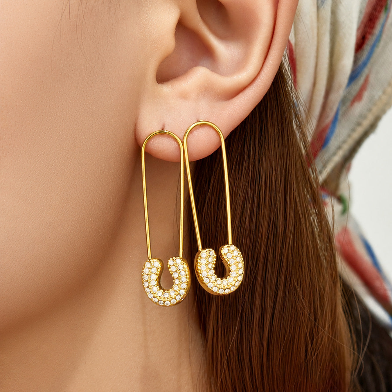 Model wearing gold cubic zirconia paperclip drop earrings