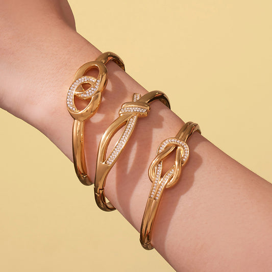 Model wearing stacked gold CZ zircon hinged bangles in three coordinated designs