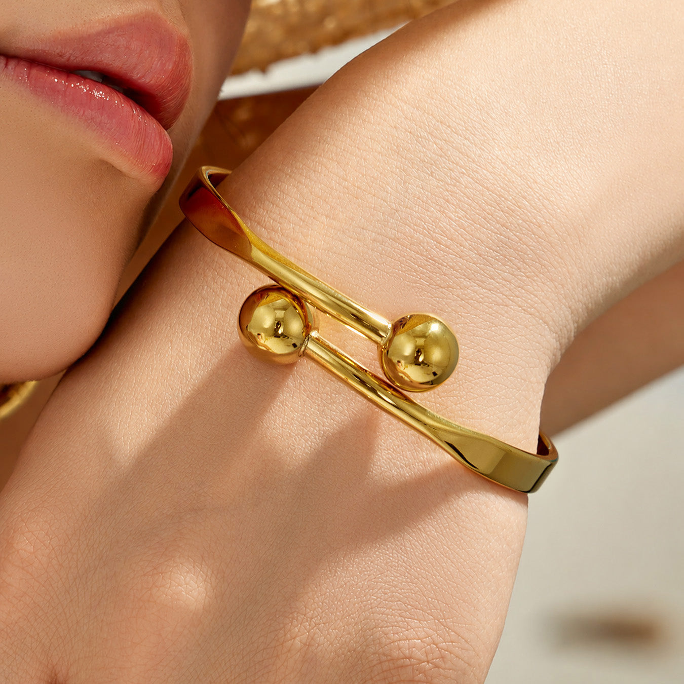 Close-up of a gold double ball cuff bracelet showing the polished spherical ends