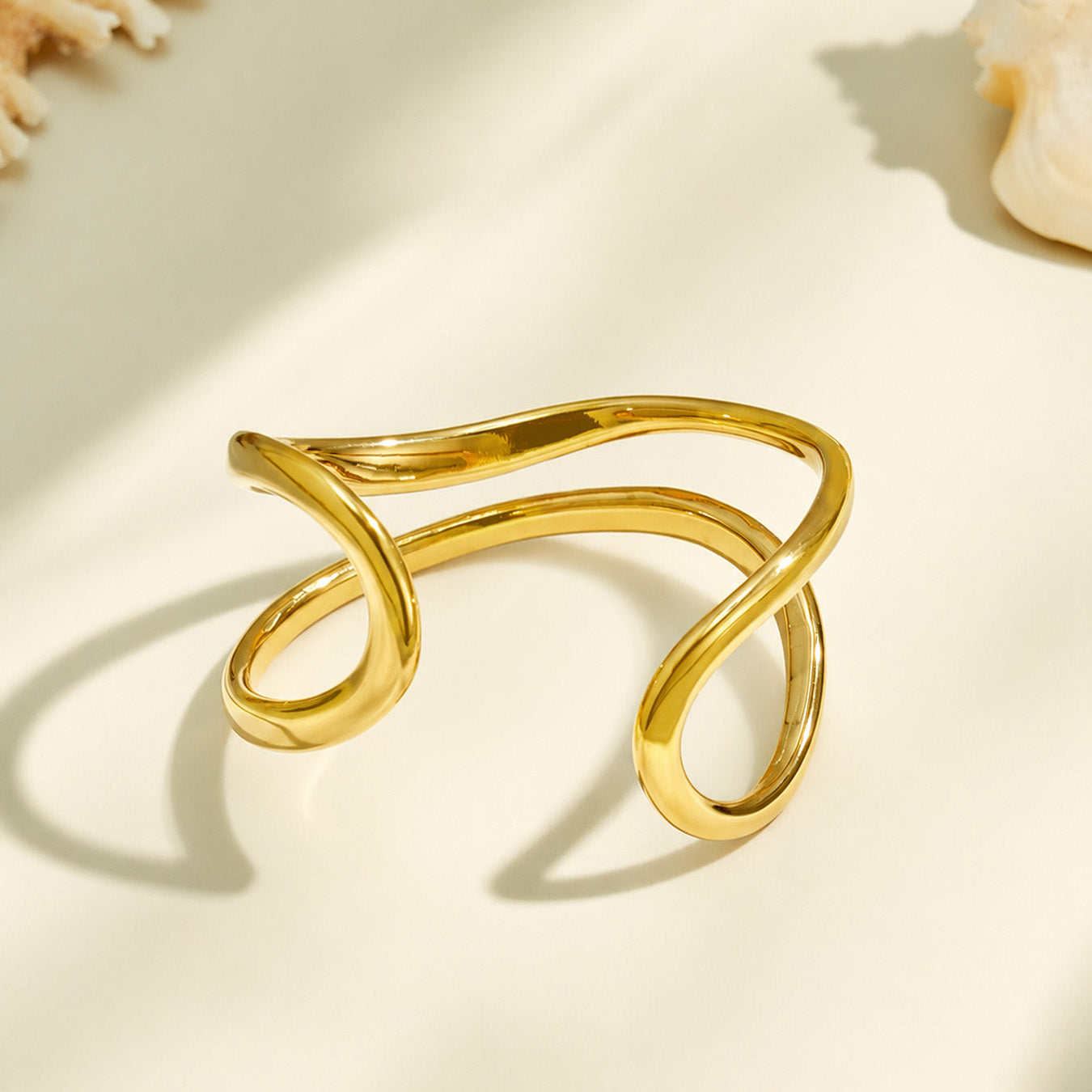 Close-up of a gold double-band cuff bracelet showing its flowing loop structure