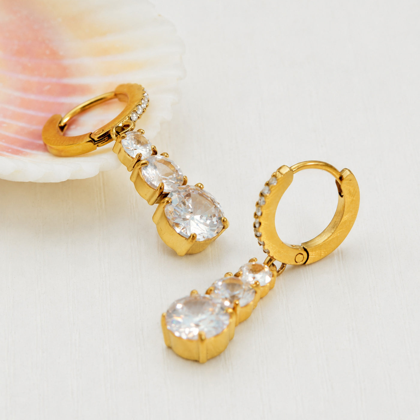 Side view of gold droplet earrings with clear cubic zirconia accents