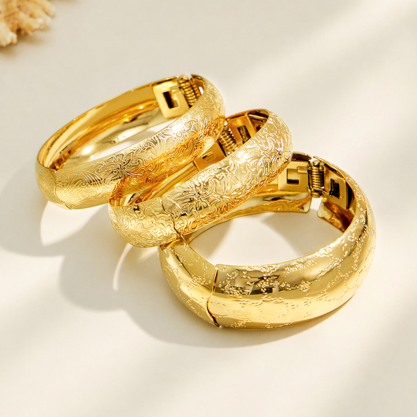Stacked gold engraved bangles with wide textured designs
