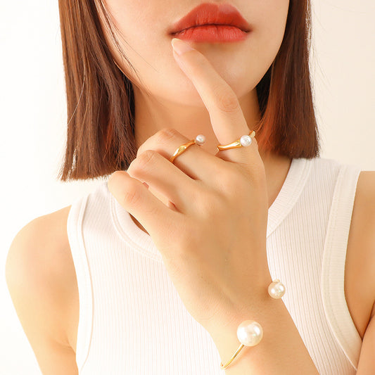Model wearing a gold-tone faux pearl open ring in a close-up hand styling shot