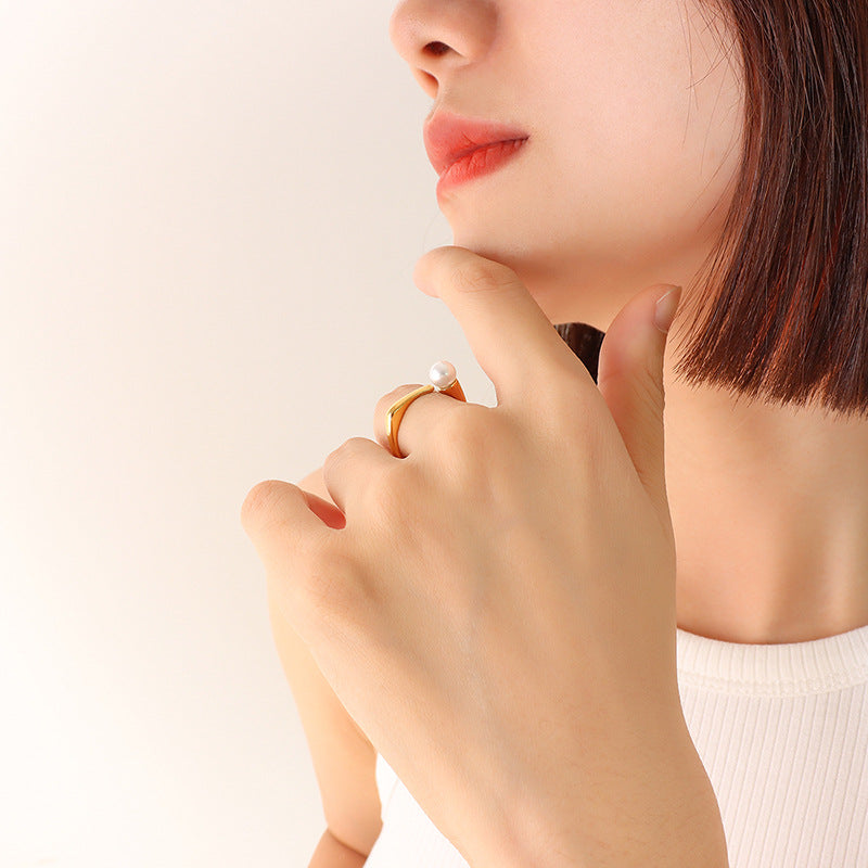 Close-up of a model wearing a gold faux pearl ring with a sculptural open-band silhouette