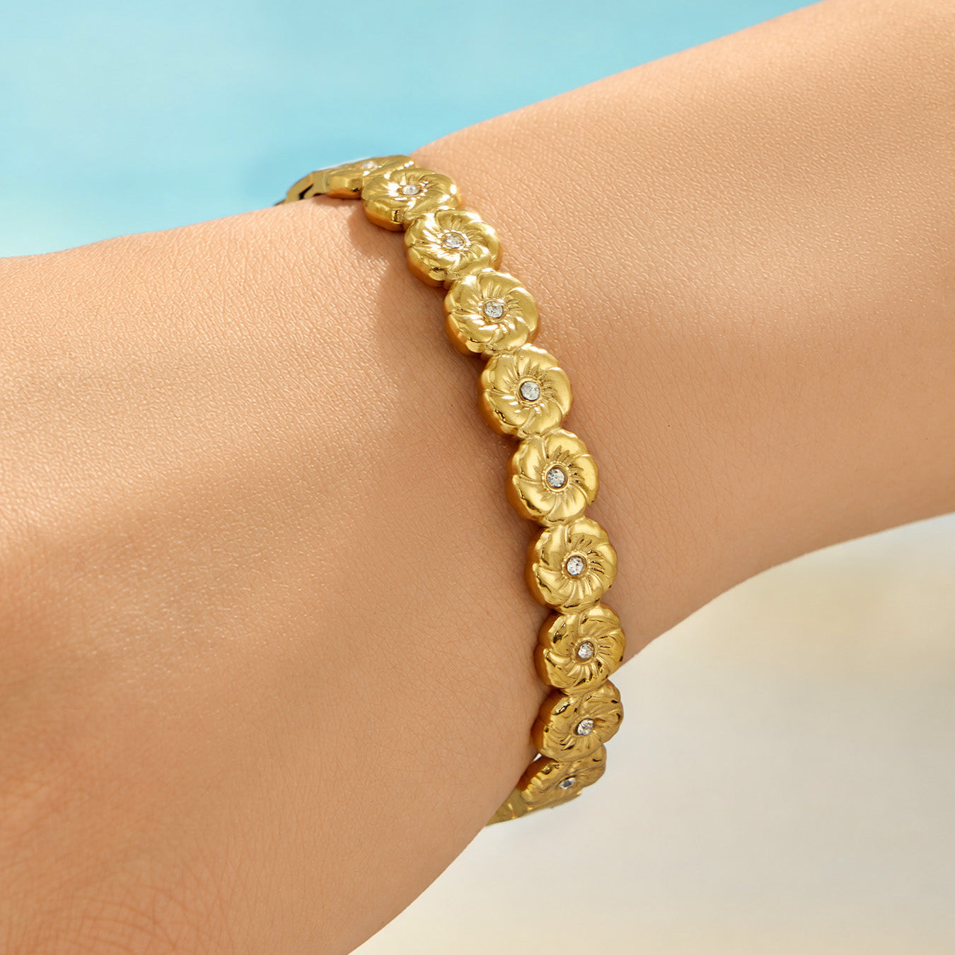 Model wearing a gold floral hinged bangle with clear cubic zirconia accents
