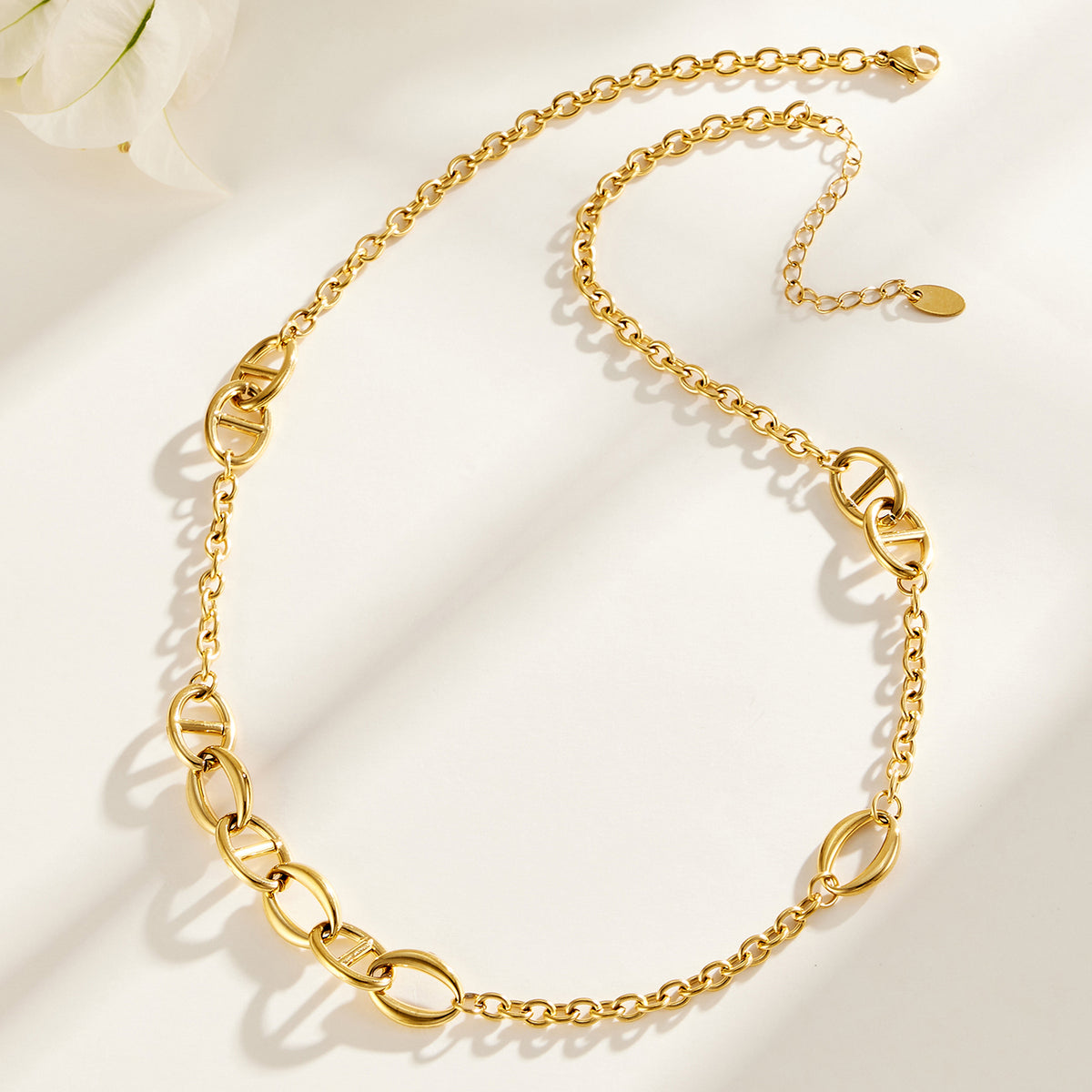 Gold geometric link necklace flat lay showing alternating oval chain details
