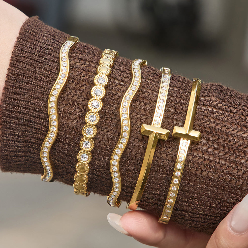 Gold zircon cuff bangle bracelet stack worn on wrist with H buckle bracelet and wavy zircon bracelet for boutique jewelry display