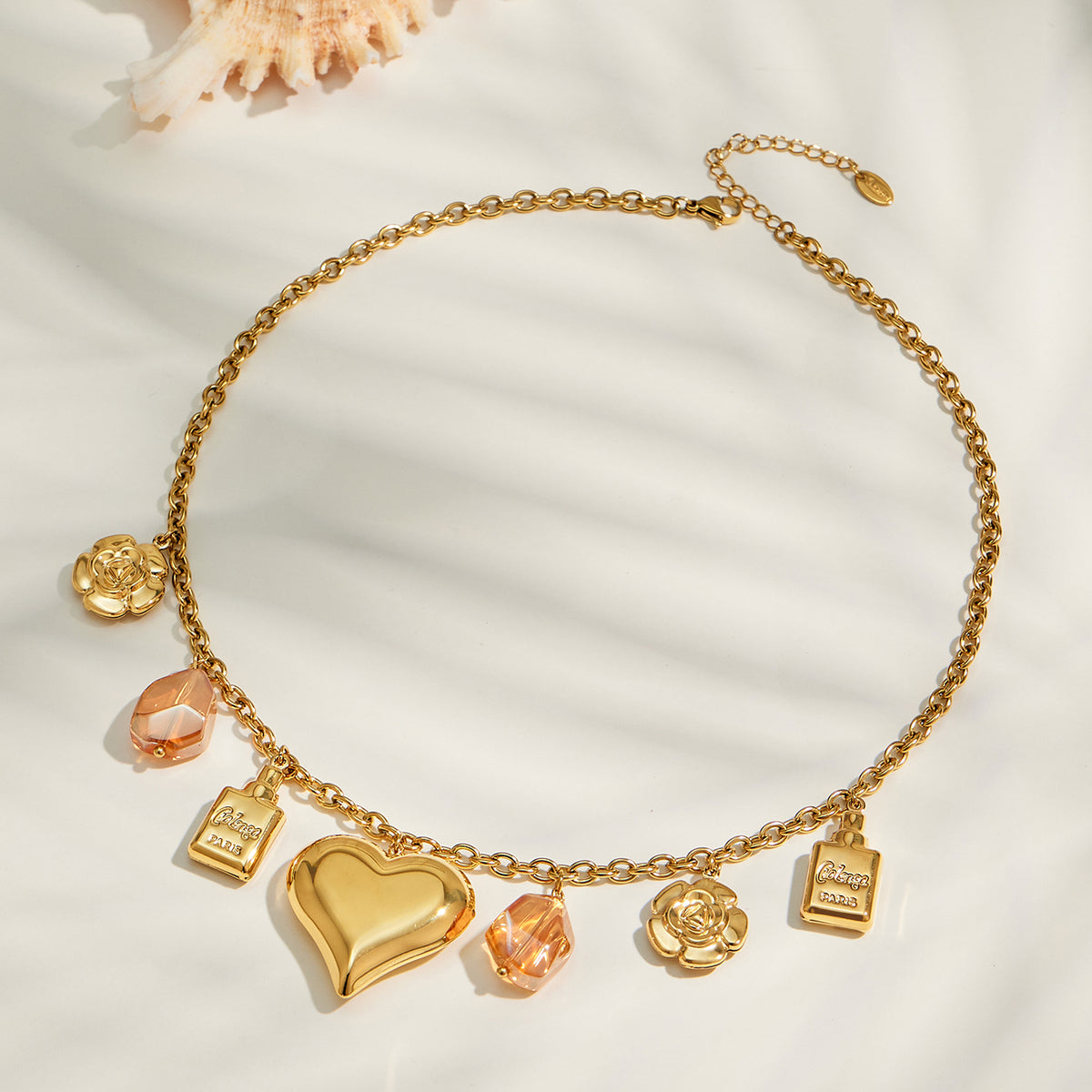 Gold heart multi-charm necklace displayed flat with resin and flower accents