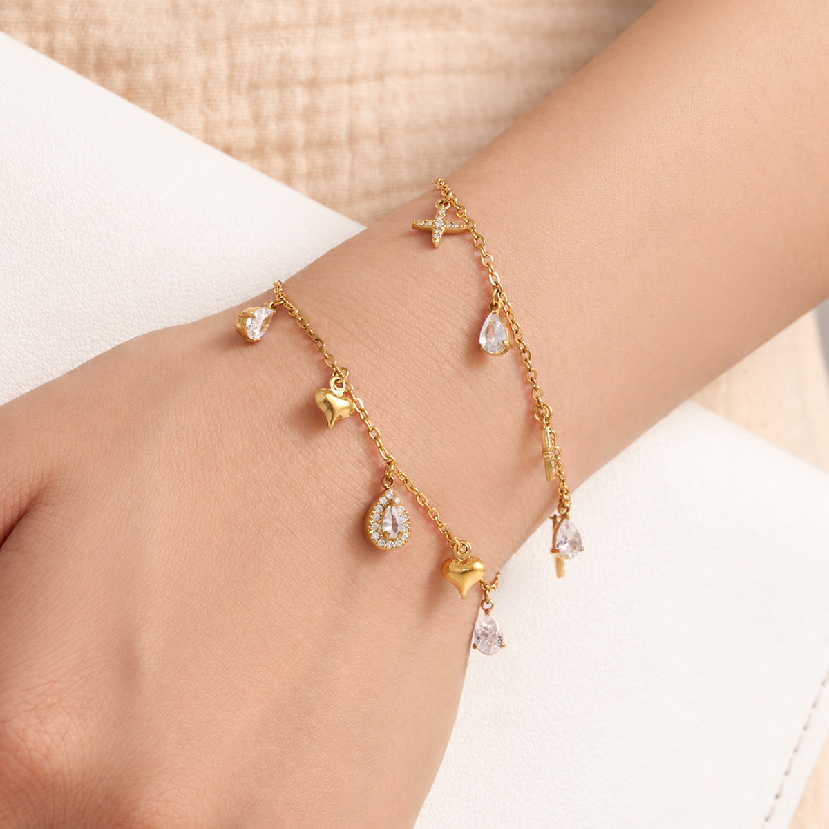 Gold heart and teardrop zircon charm bracelet worn on wrist