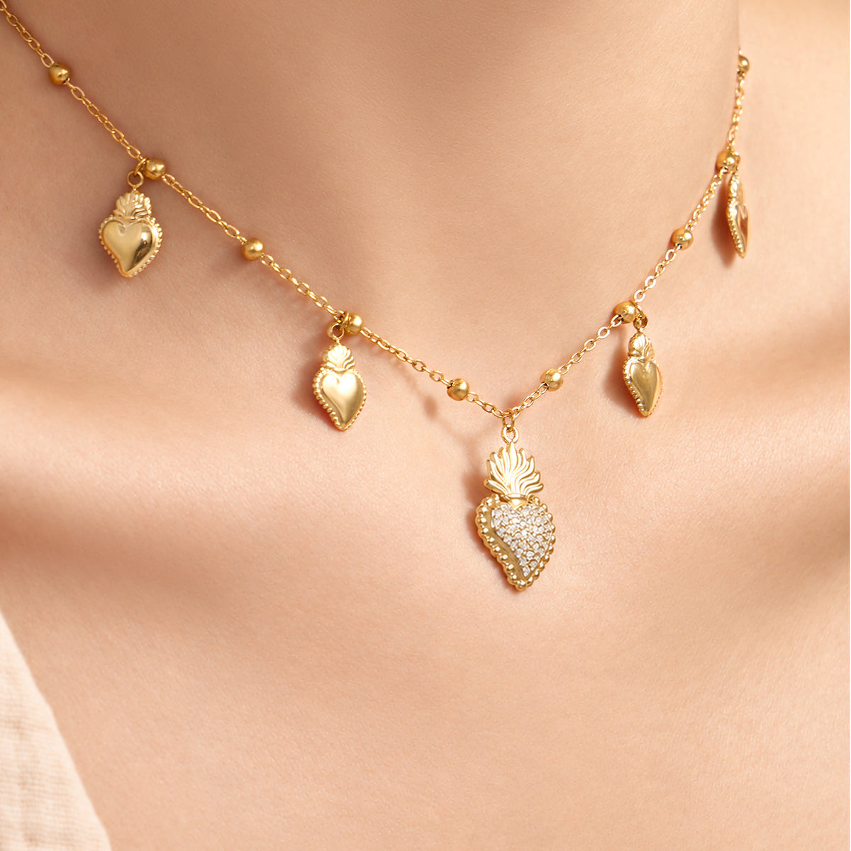 Close-up of gold-tone heart zircon charm necklace with multiple dangling heart details