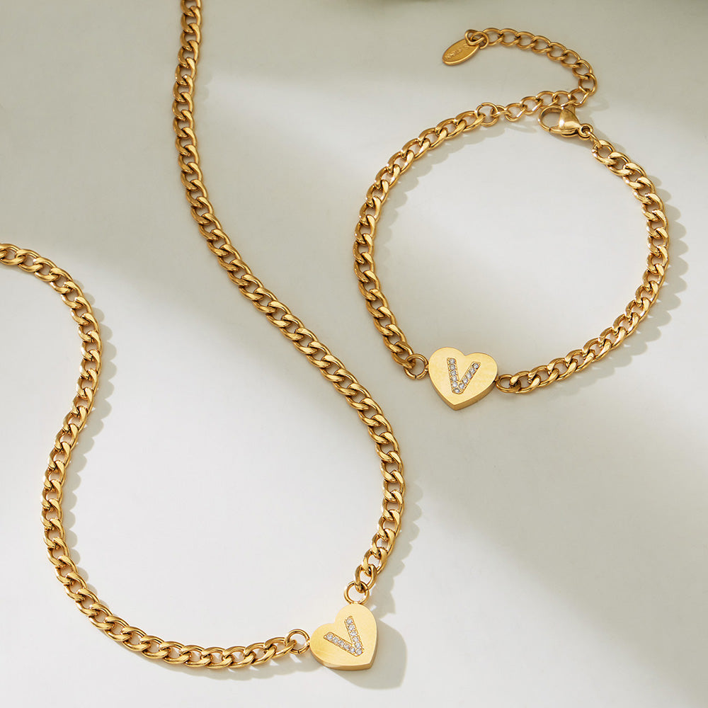 Gold-tone zircon initial heart curb chain necklace and bracelet shown in a close-up flat lay