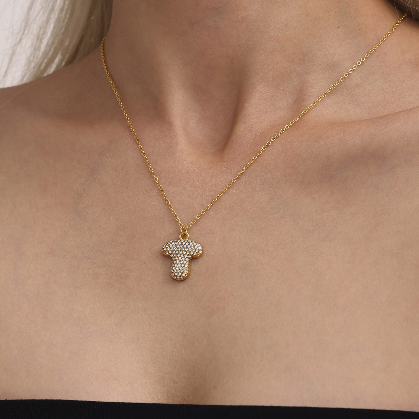 Model wearing gold letter T iced out initial necklace with zircon pave pendant for everyday personalized jewelry