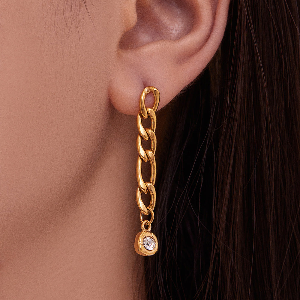 Close-up ear view of a gold long link chain earring with a zircon drop