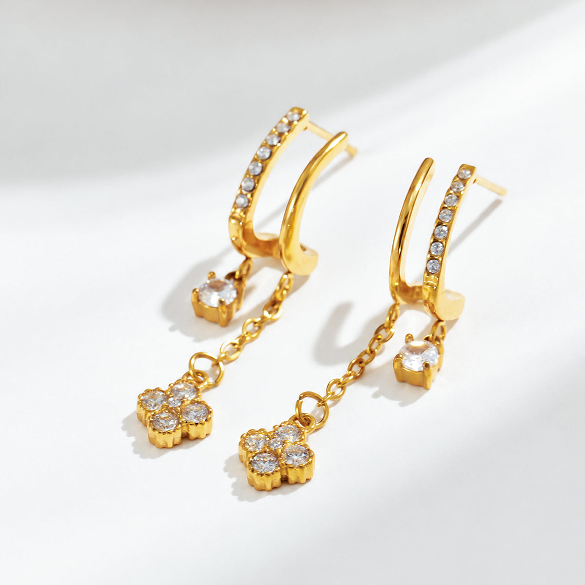 Gold-tone stainless steel long CZ dangle earrings displayed for wholesale buyers
