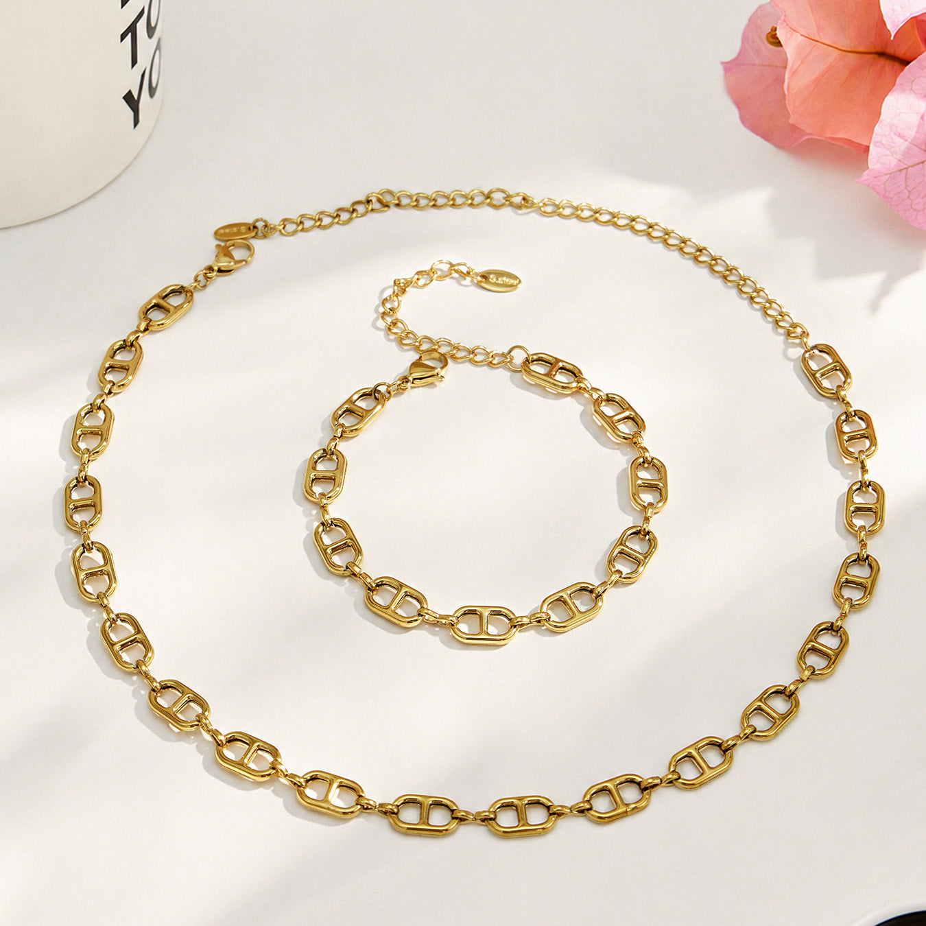 Gold mariner chain link necklace and bracelet arranged together in a circular flat lay