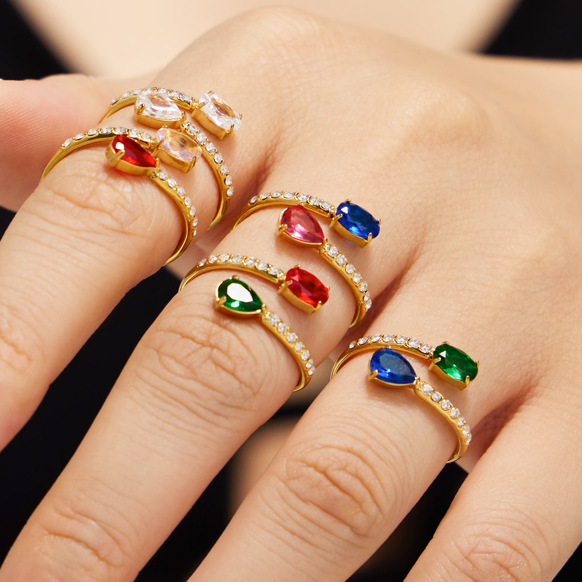 Gold-tone open rings with white cubic zirconia and colorful glass stones styled on fingers