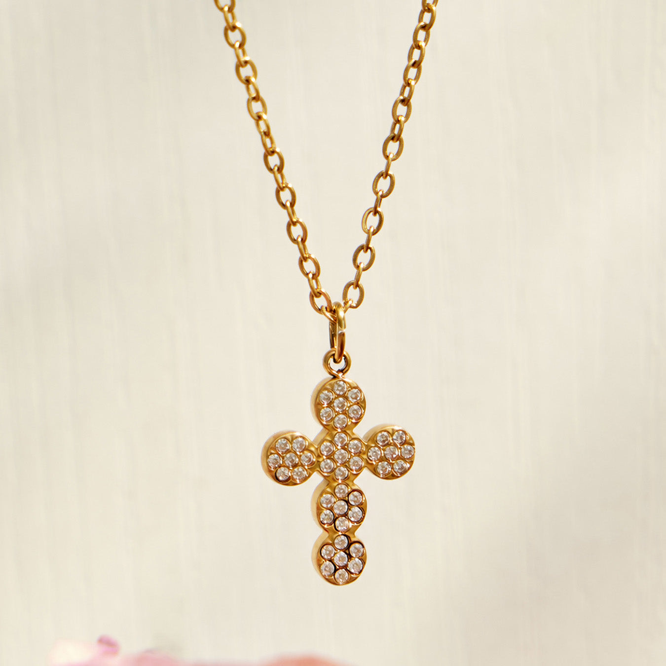 Close-up of a gold pavé zircon cross pendant on a fine chain