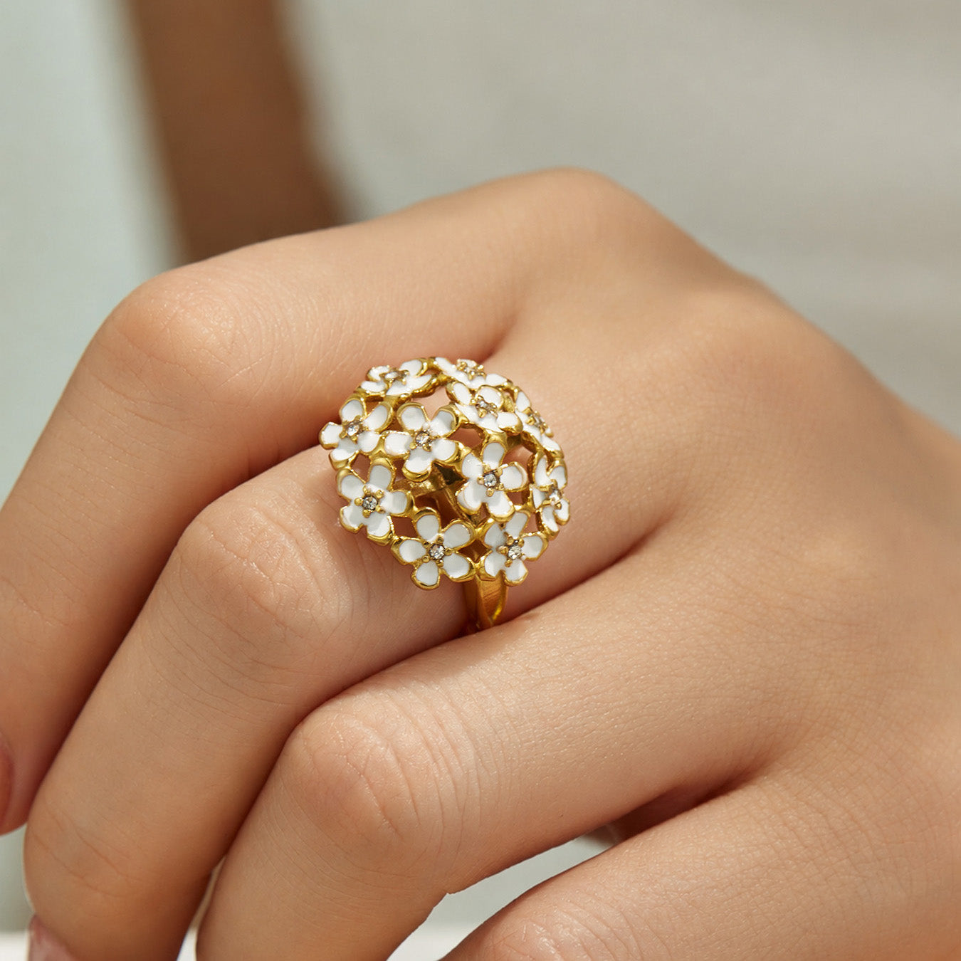 Model wearing a gold pave floral cubic zirconia statement ring on the finger