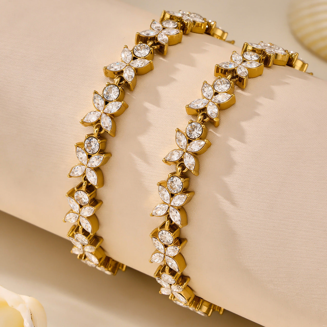 Pair of gold pavé zircon tennis bracelets displayed on soft neutral fabric