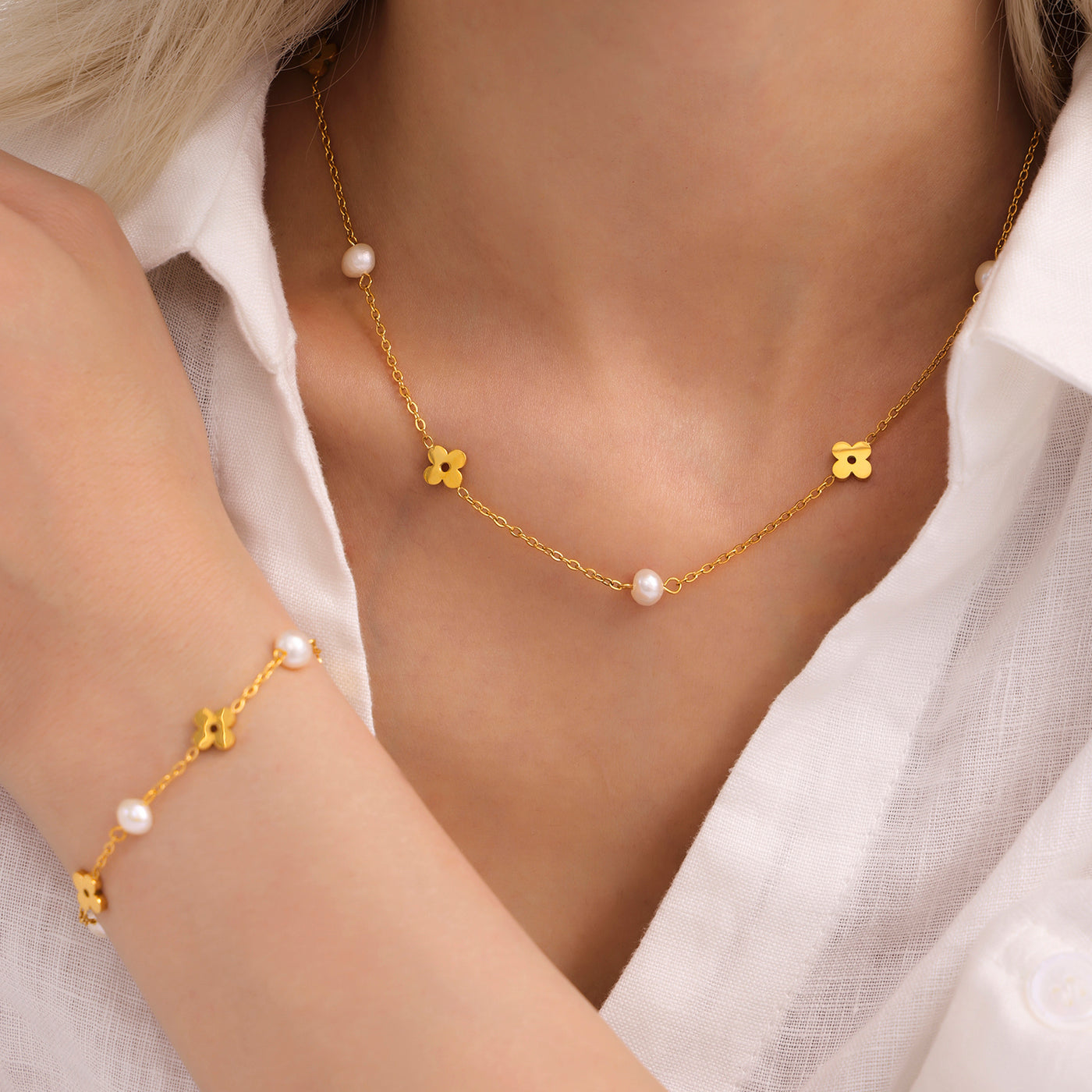 Model wearing a gold pearl clover necklace with small freshwater pearl accents around the neckline