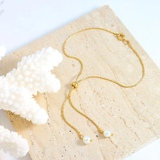 Gold pearl lariat necklace and slider bracelet wholesale flat lay