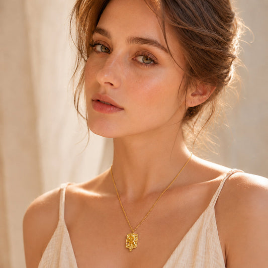 Model wearing a gold textured rectangular pendant necklace with a white outfit