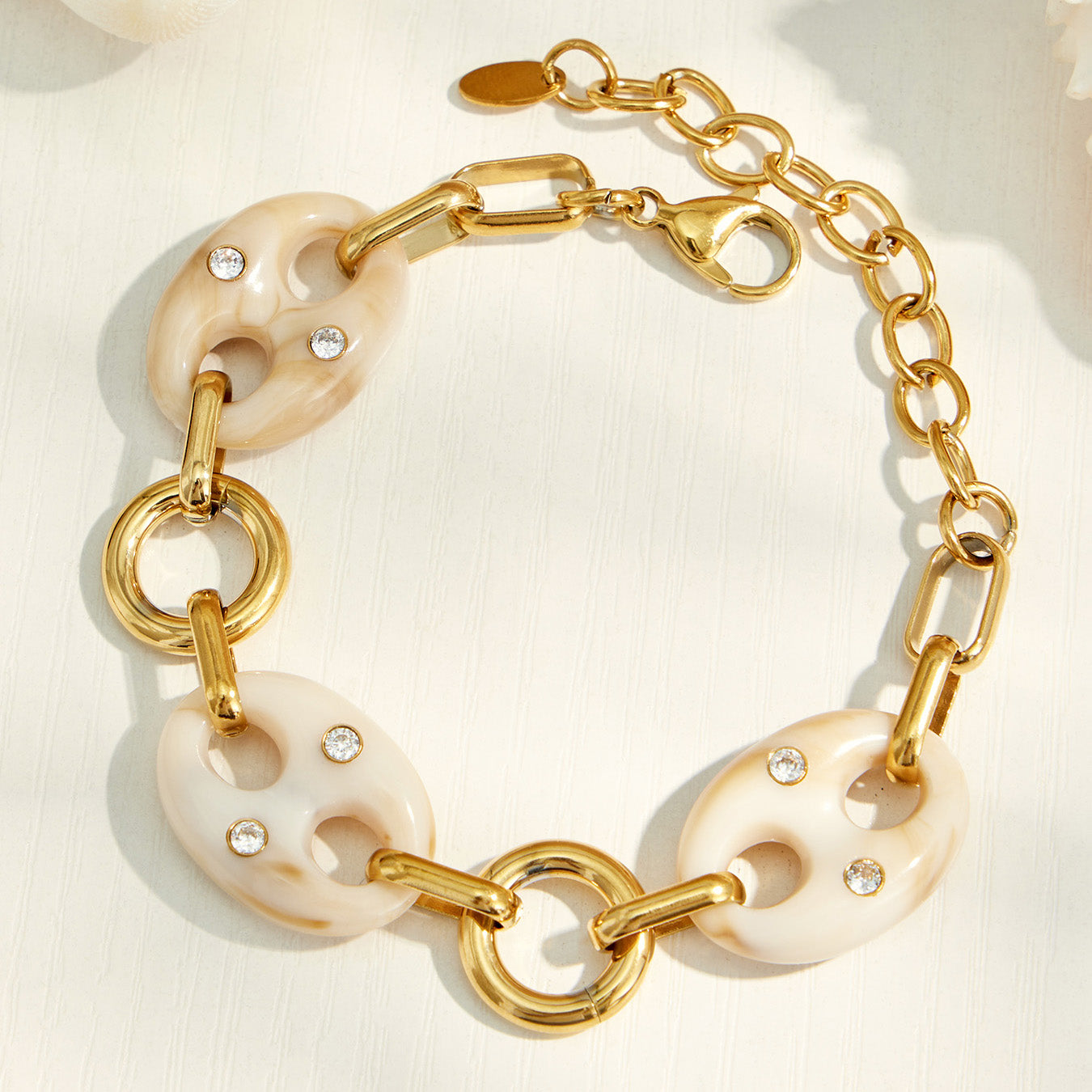 Close-up of a gold bracelet with cream resin mariner links and adjustable chain