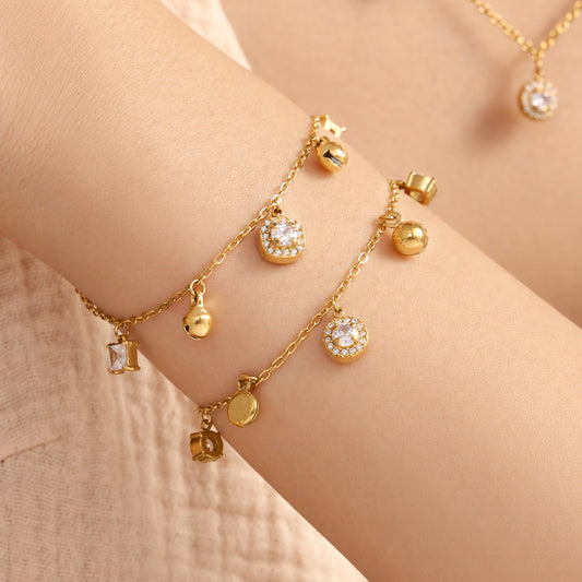Gold tone stainless steel round and square zircon bracelets worn together on wrist close up