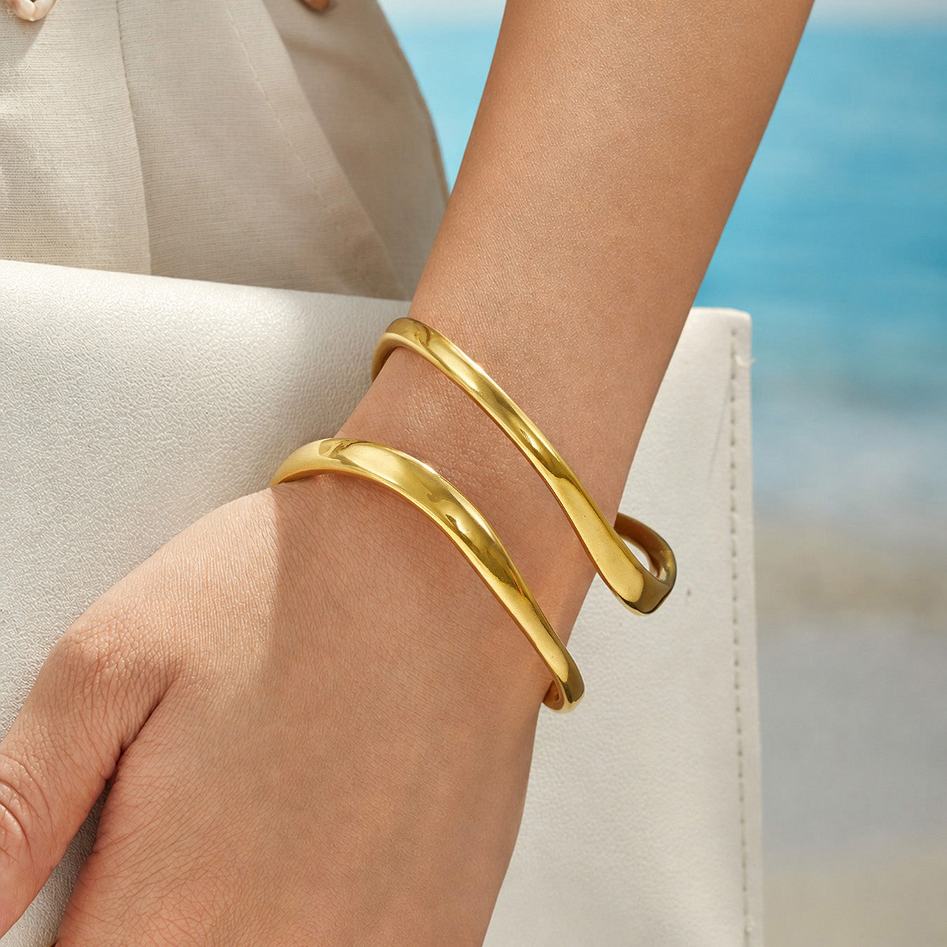 Close-up of a gold sculptural cuff bracelet with smooth rounded double loops