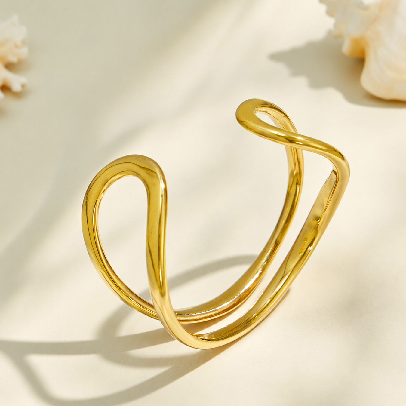 Angled product view of a sculptural gold double loop cuff bracelet