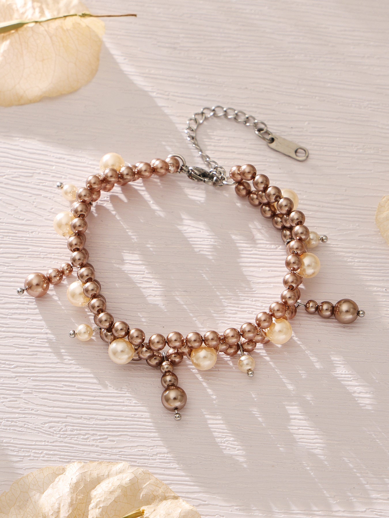 Gold-tone shell pearl tassel bracelet displayed in a circular flat lay