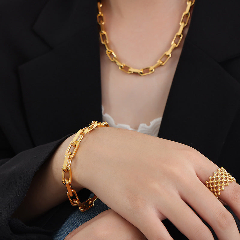 Model wearing a gold stainless steel chunky chain bracelet with a black blazer