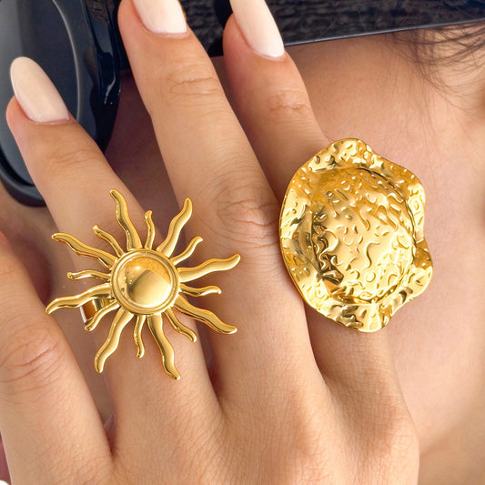 Gold-tone stainless steel sun and textured disc rings worn side by side on fingers