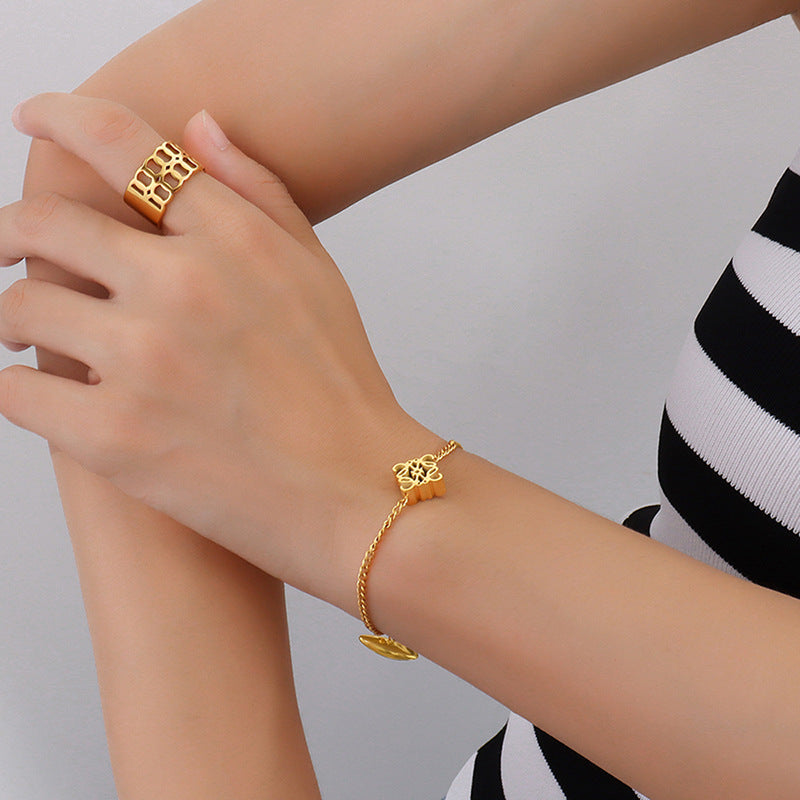 Model wearing a gold-tone symbol charm chain bracelet with hand styling