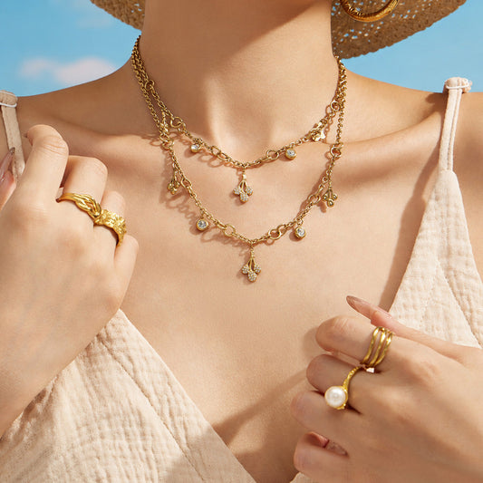 Gold teardrop zircon necklace and matching bracelet styled together on a model by the beach