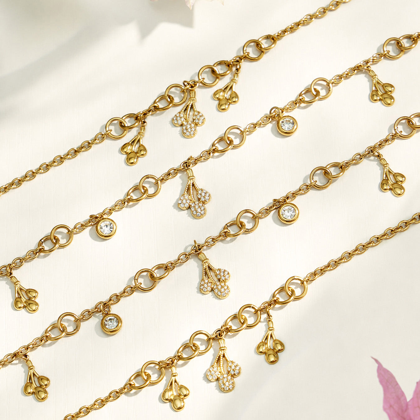Gold chain jewelry with multiple teardrop zircon charms shown in a detailed flat lay