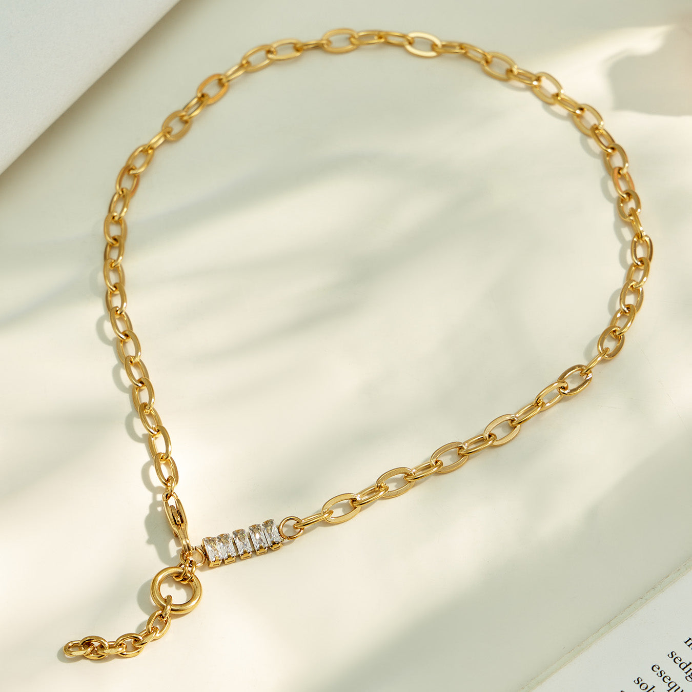 Gold toggle lariat necklace arranged on neutral fabric with a Y-shaped chain drop