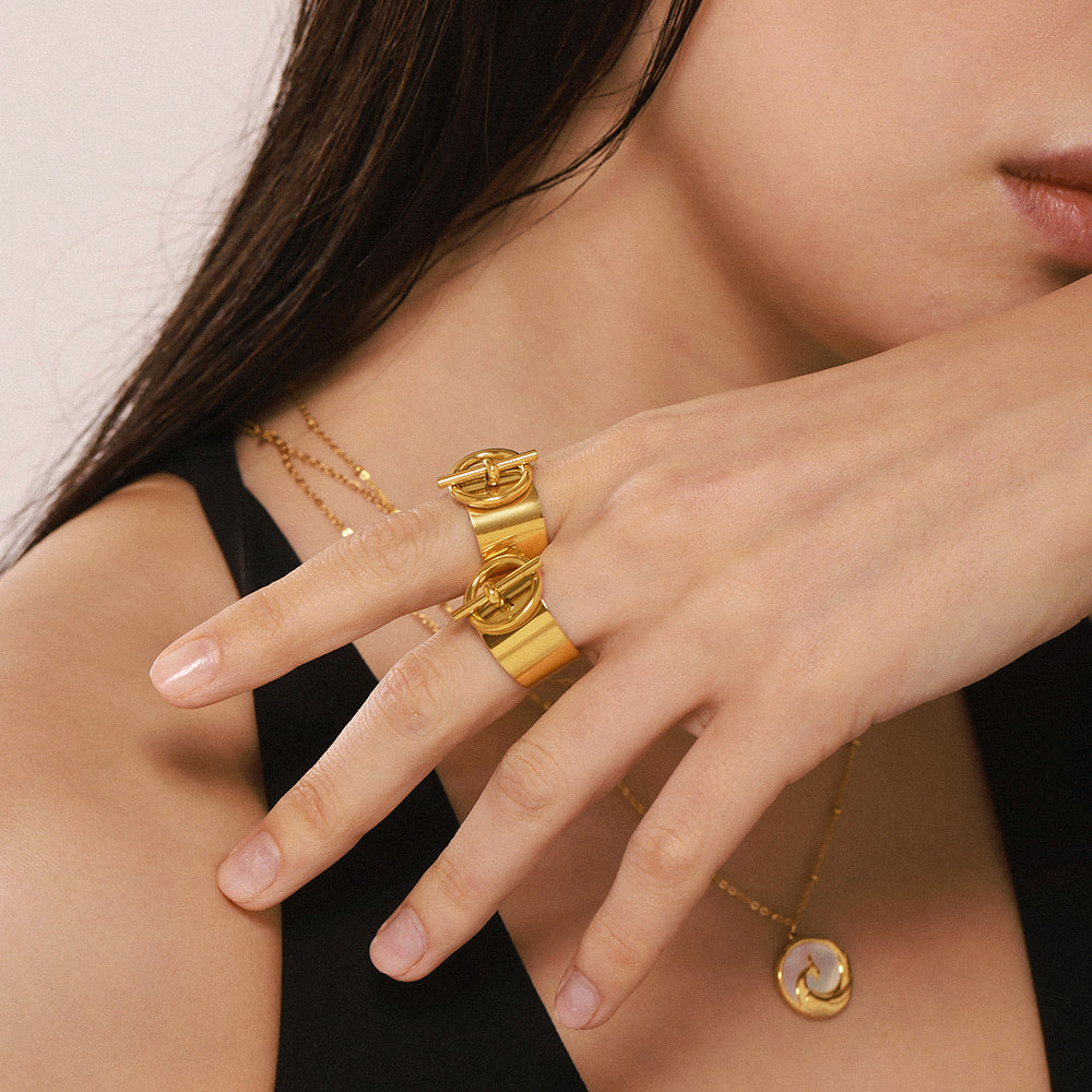 Gold tone wide band stainless steel open ring shown on a model hand