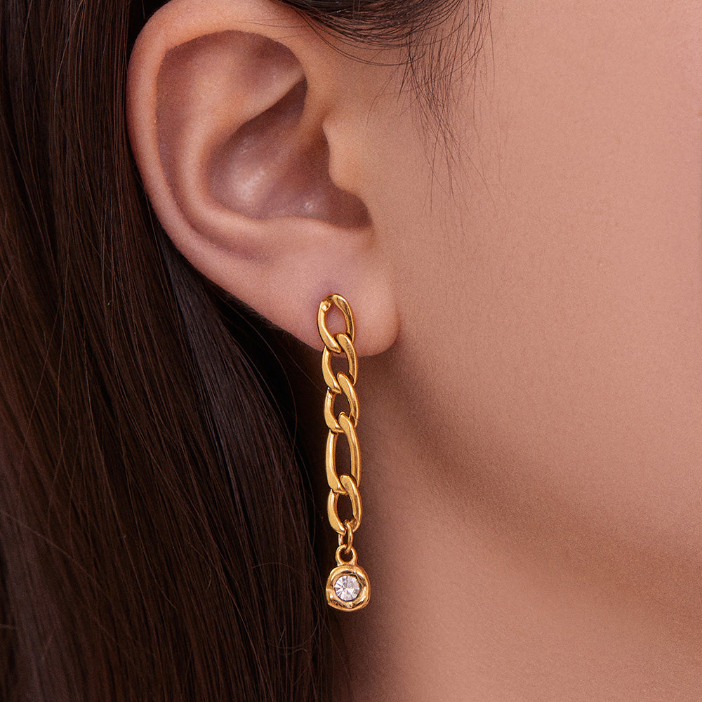 Profile view of a model wearing a gold chain drop earring with clear zircon detail