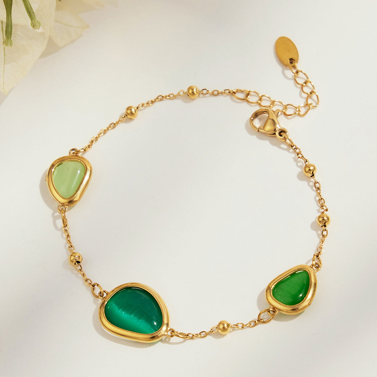 Gold-tone bracelet with green cat eye stone accents and geometric settings