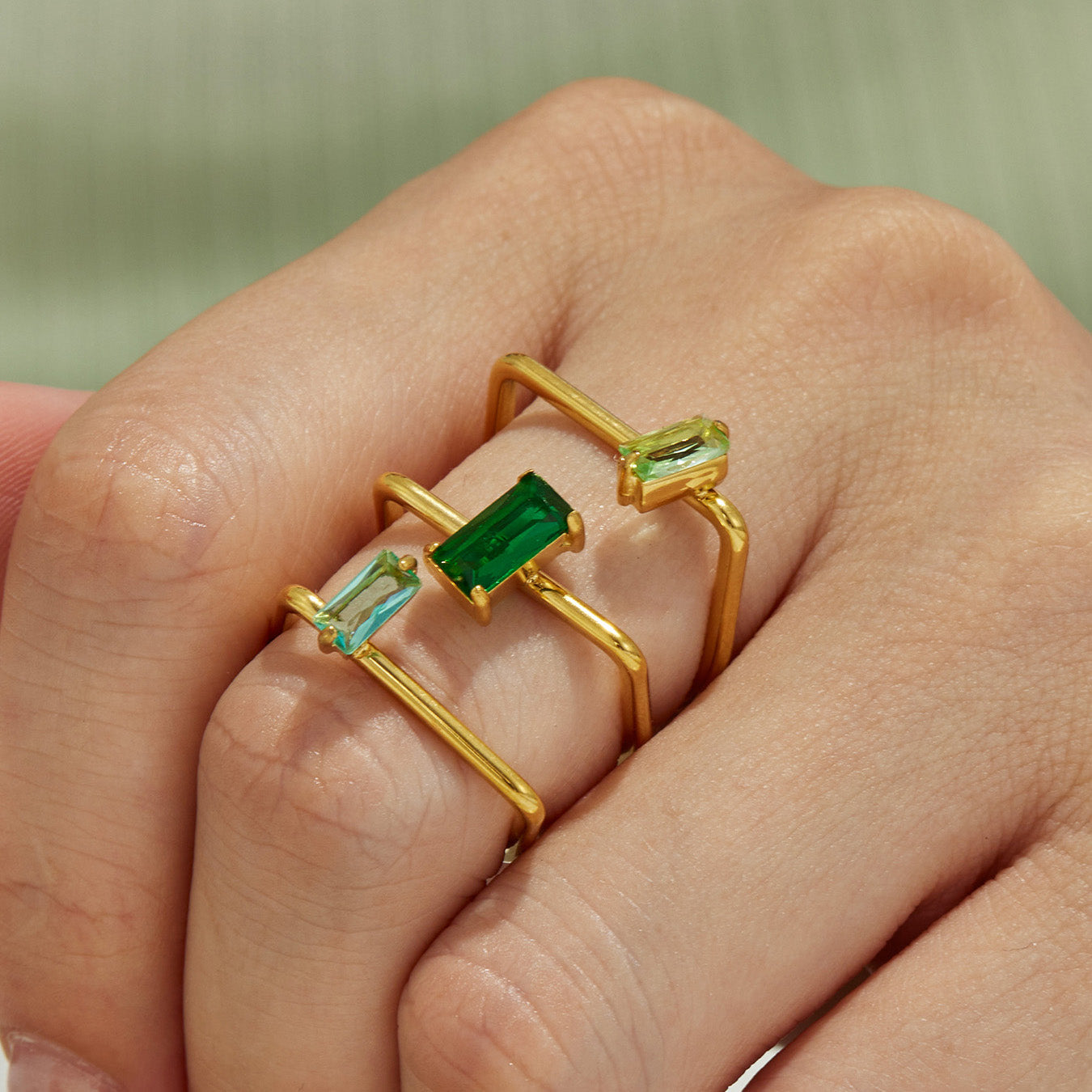 Close-up of a green rectangular CZ multi-band 316L stainless steel gold ring