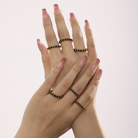 Model wearing a green glass eternity ring with other gold rings on the hand