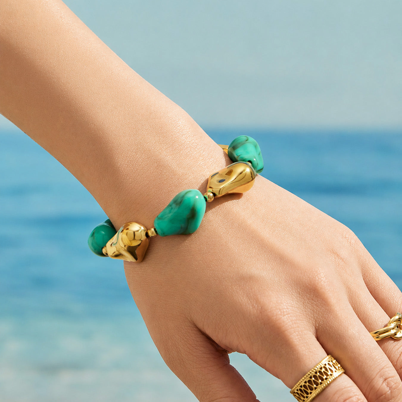 Green chunky resin bracelet with organic beads and sculptural gold accents worn on the wrist